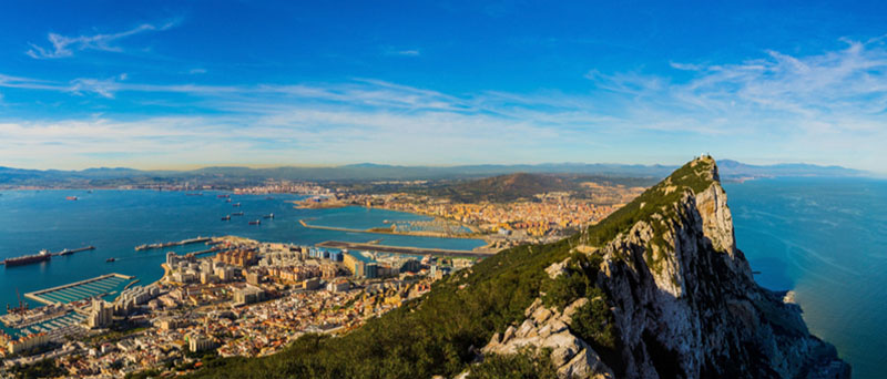 A panoramic view of the Rock of Gibraltar rising above the sea with clear skies